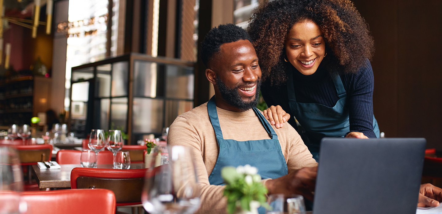 couple who own a restaurant they secured with a commercial property loan reading details on their computer